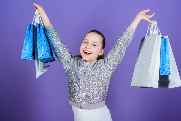 Get better looking. Black friday. Sale discount. Shopping day. Child hold bunch packages. Kids fashion. Birthday girl. Surprise gift. Girl with shopping bags violet background. Shopping and purchase - Photo, Image
