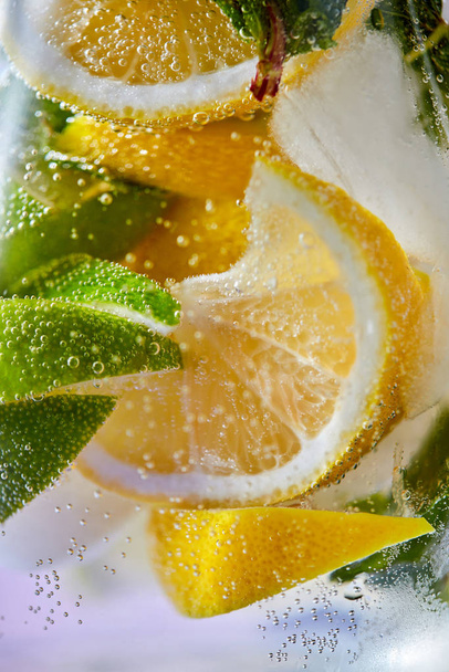 Macro photo of fresh lime and lemon slices with bubbles in the glass. Summer cold drink - Φωτογραφία, εικόνα