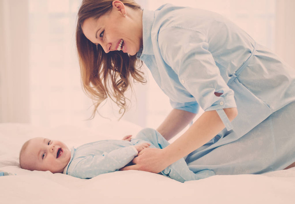 Ευτυχισμένος μέσης ηλικίας η μητέρα με το παιδί σε ένα κρεβάτι - Φωτογραφία, εικόνα