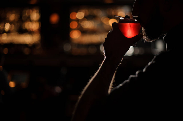 Darkened shot of bartender sipping alcohol drink - Fotó, kép