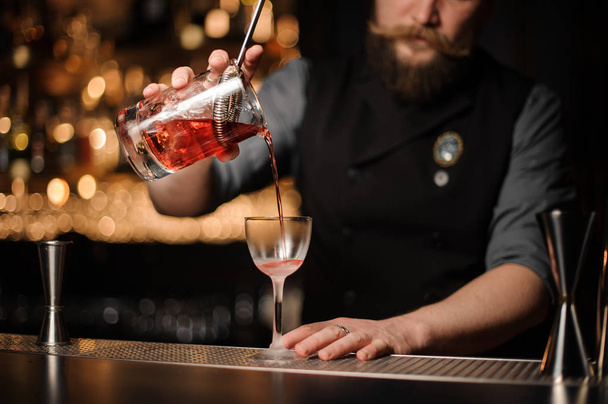 Male bartender pours alcohol cocktail with strainer - Fotó, kép