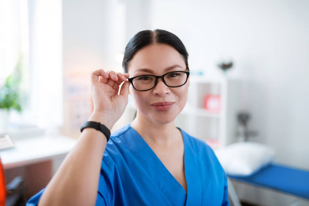 Good-looking Asian doctor touching her clear glasses - Fotografie, Obrázek