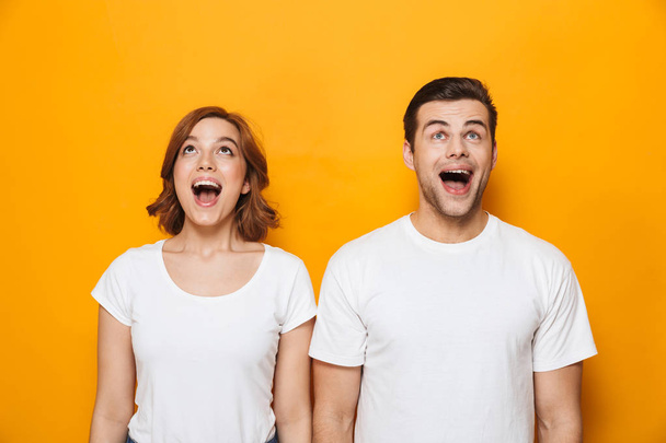 Excited beautiful couple wearing white t-shirts standing - Фото, изображение