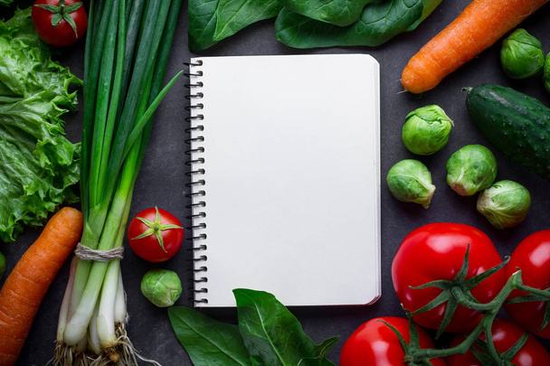 Libro de recetas en blanco y varias verduras maduras para cocinar frescas
  - Foto, Imagen