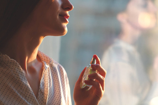 Stylish woman in blouse spraying a bottle of favorite perfume at - Foto, Bild