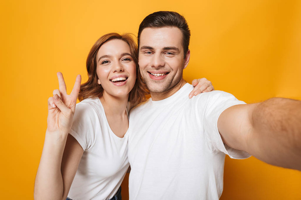 Excited beautiful couple wearing white t-shirts standing - Fotoğraf, Görsel