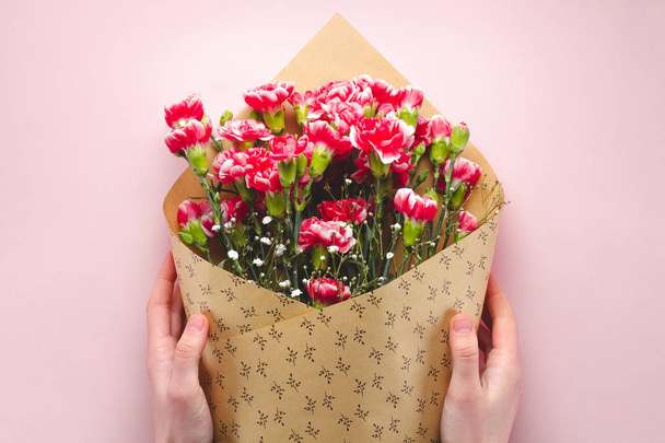 A bouquet of flowers in craft paper on a pink background. Floris - Fotoğraf, Görsel