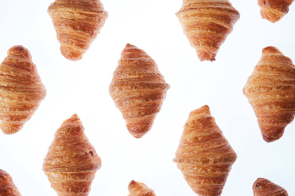 Delicious freshly baked crispy croissants pattern on a light background. Close up. Continental breakfast. - Photo, Image
