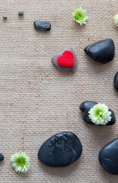 Ambiente de spa com coração de amor, flores e pedras pretas em um pano de fundo
. - Foto, Imagem