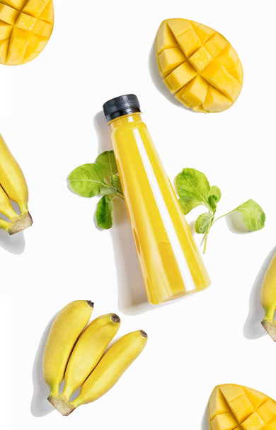 top view flat lay yellow bottle of juice with spinach, mango and banana  isolated on white background. Healthy lifestyle, vegetarian food concept. Detox  - Φωτογραφία, εικόνα
