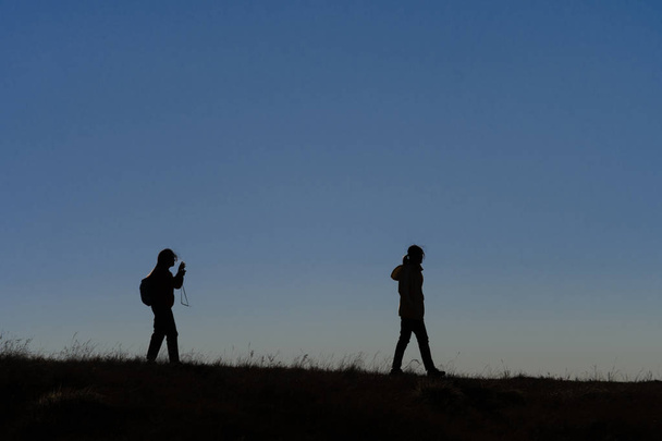 Silhouettes of hikers with backpacks enjoying sunset view from t - Photo, Image