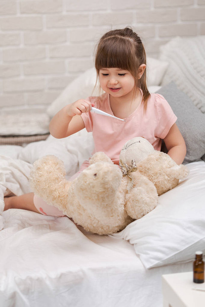cute child girl playing doctor with teddy bear - Foto, afbeelding