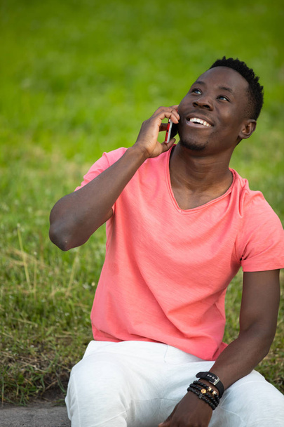 African american man in living coral t-shirt talking by smartphone - Valokuva, kuva