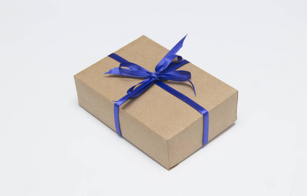 Kraft gift box with blue ribbon is on a white background - Zdjęcie, obraz