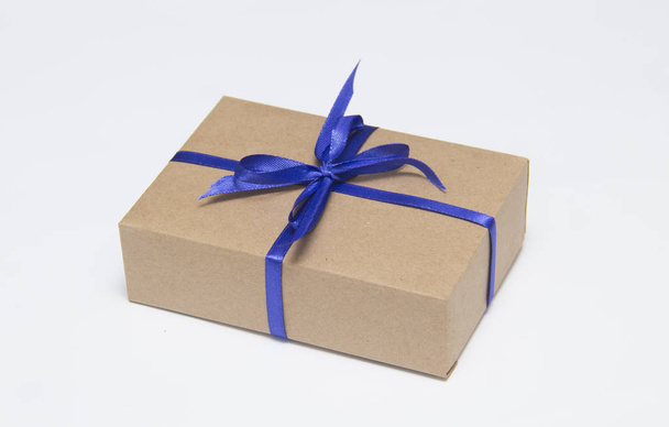 Kraft gift box with blue ribbon is on a white background - Фото, зображення