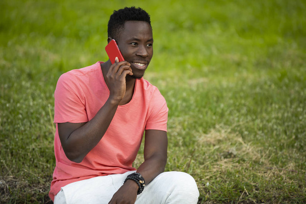 African american man in living coral t-shirt talking by smartphone - 写真・画像
