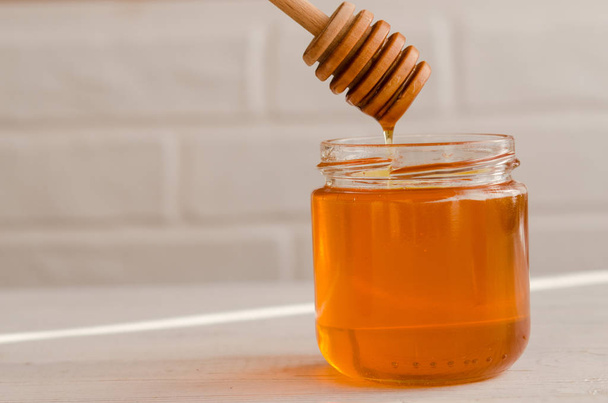 Polyfloral honey flows from a wooden honey spoon. - Φωτογραφία, εικόνα