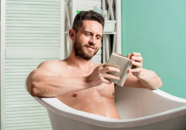 Relax at home. Total relaxation. Personal hygiene. Nervous system benefit bathing. Relax concept. Man muscular torso relax bathtub and read book. Relaxed guy reading book while relaxing in hot bath - 写真・画像