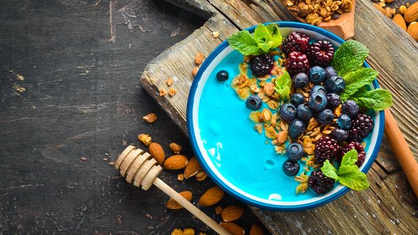 Blue Spirulina and Fresh Fruit Smoothie Bowl Topped with blackberries, blueberries, granola and yogurt. Breakfast. Top view. Free space for your text. - 写真・画像
