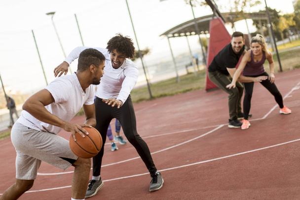 Grupo de jovens multiétnicos jogando basquete na quadra
 - Foto, Imagem
