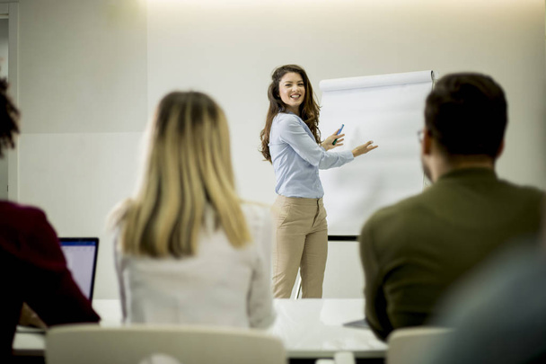 kreative positive weibliche Führungskraft spricht mit Studenten während eines Workshops im kleinen Büro über Businessplan - Foto, Bild