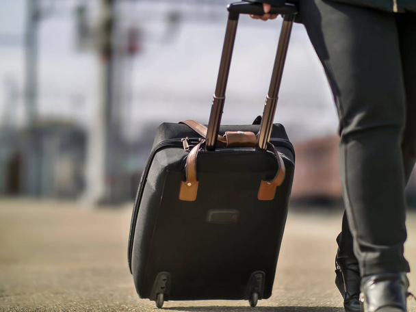 Κορίτσι ρολό μια μαύρη βαλίτσα στην σιδηροδρομική πλατφόρμα, κοντινό - Φωτογραφία, εικόνα