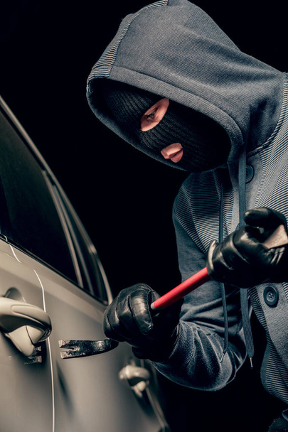 erkek hırsız bir levye ile araba kapısını açmak için gidiyor. - Fotoğraf, Görsel