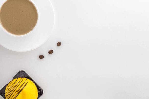 Белая чашка горячего кофе и корицы палочки и манго сладкий торт
. - Фото, изображение