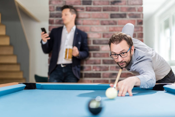 Two young businessmen playing snooker game. - Фото, изображение