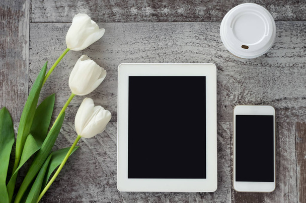 White tablet, phone, coffee and flowers are on the table. Work a - Fotografie, Obrázek