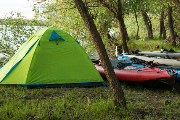 палатка и каяки в кемпинге в лесу у реки
 - Фото, изображение