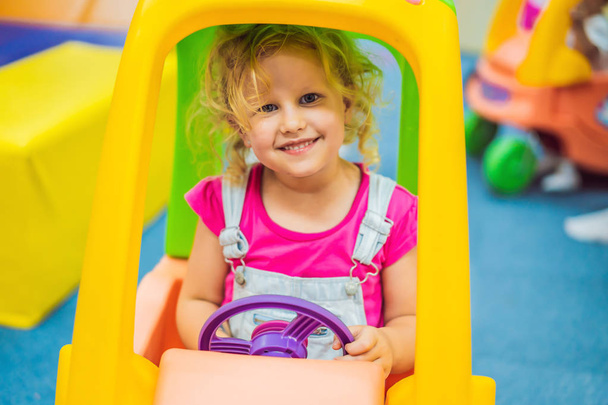 Little girl rides a toy colorful car - Foto, imagen