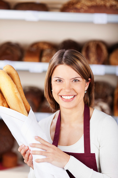 Happy bakery worker with baguettes - Photo, image