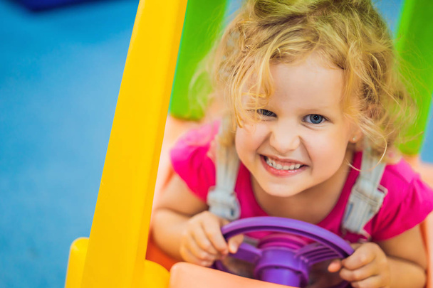 Little girl rides a toy colorful car - Фото, зображення