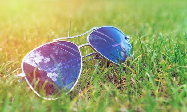 Mise au point douce, lunettes de soleil sur l'herbe verte, humeur estivale
. - Photo, image