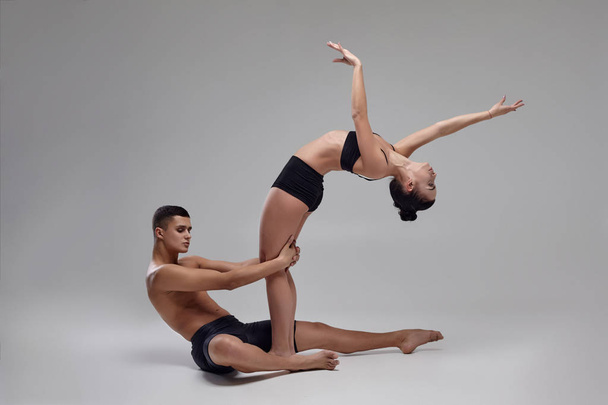 Siyah takım elbiseli genç bir modern bale dansçısı çift gri bir stüdyo arka plan üzerinde poz. - Fotoğraf, Görsel