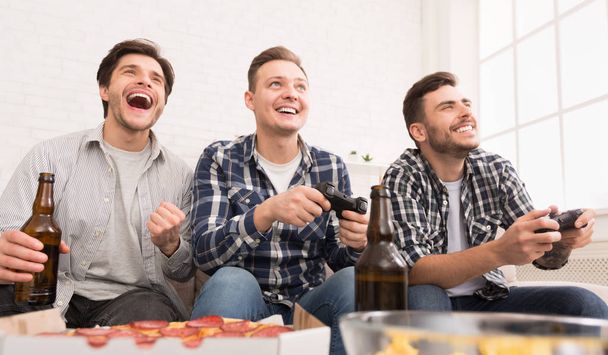 Bachelor mens leven. Vrienden spelen video games met bier en pizza - Foto, afbeelding