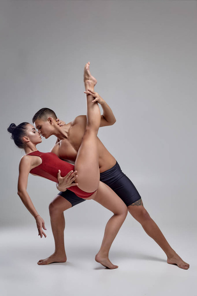 Para sportowych współczesnych tancerzy baletowych są stwarzające przed szarym tle Studio. - Zdjęcie, obraz