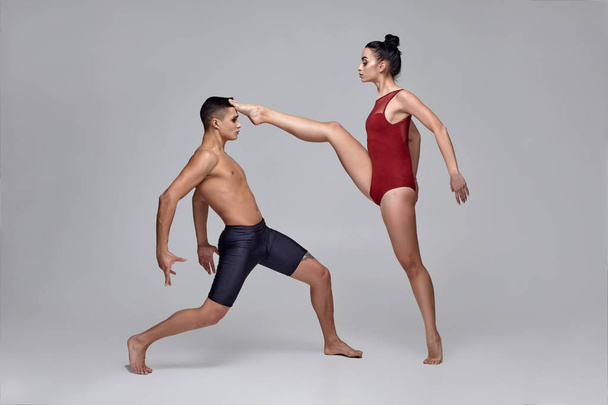 The couple of an athletic modern ballet dancers are posing against a gray studio background. - Fotoğraf, Görsel