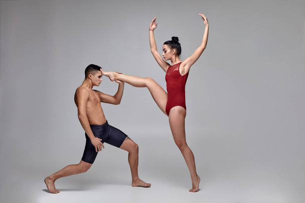 O casal de um atlético bailarinos modernos estão posando contra um fundo de estúdio cinza
. - Foto, Imagem