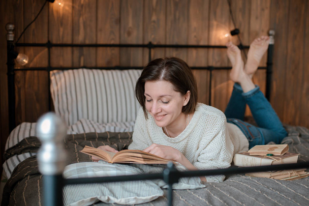 girl reading a book and drinking coffee in bed feet on the wall. - Photo, Image