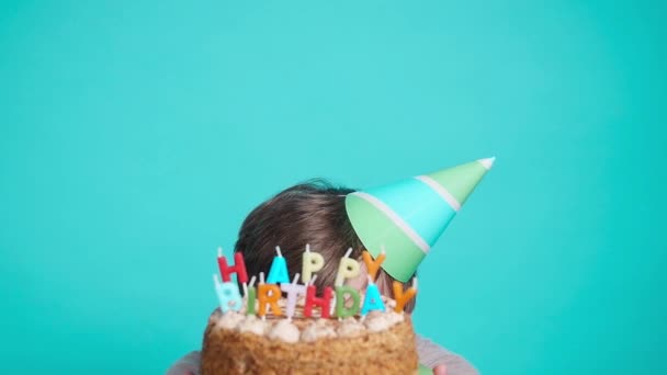 Koncepció az ünneplés és a szórakozás. Mosolygó boldog őrült fiatalember fél kalap gazdaság születésnapi torta - Felvétel, videó