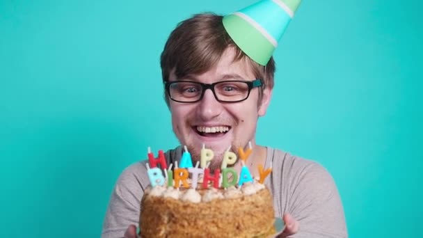 Concept de célébration et de plaisir. Souriant heureux fou jeune homme en chapeau de fête tenant un gâteau d'anniversaire
 - Séquence, vidéo
