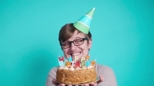 Concepto de celebración y diversión. Sonriendo joven loco feliz en sombrero de fiesta sosteniendo un pastel de cumpleaños
 - Metraje, vídeo