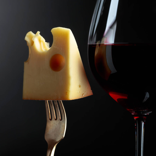  Siyah bir arka plan üzerinde kırmızı şarap ile Maasdam peyniri. - Fotoğraf, Görsel