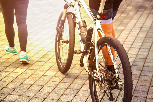 νεαρό ζευγάρι με ποδήλατο στην πόλη το ηλιοβασίλεμα. Έννοια του αθλητισμού.  - Φωτογραφία, εικόνα