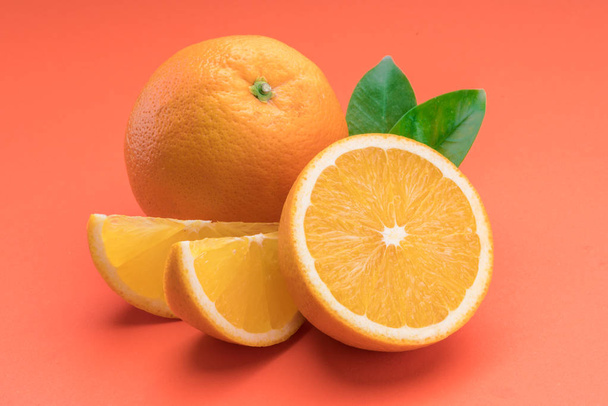 Orange fruit with orange slices and leaves isolated on orange ba - Foto, Imagem