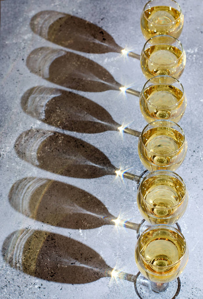 White wine in glass glasses. Blue background. Dark shadows from glasses - Photo, Image