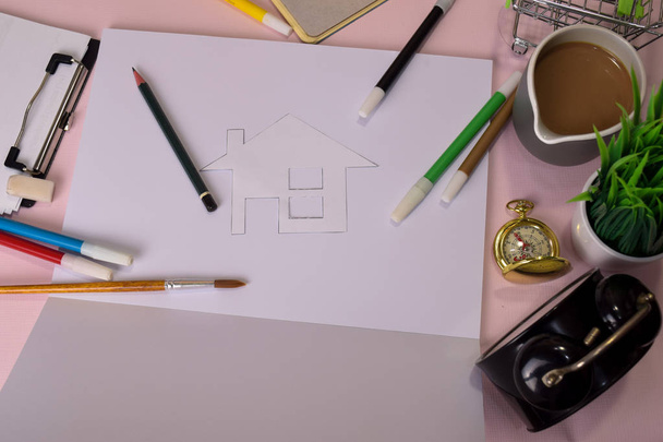 Top näkymä leikkuupaperin tai piirustus talon vaaleanpunainen pöytä, valmistautuu tekemään kotitehtäviä avoimessa muistikirjassa. Piirustuksen työpöytäkonsepti
. - Valokuva, kuva