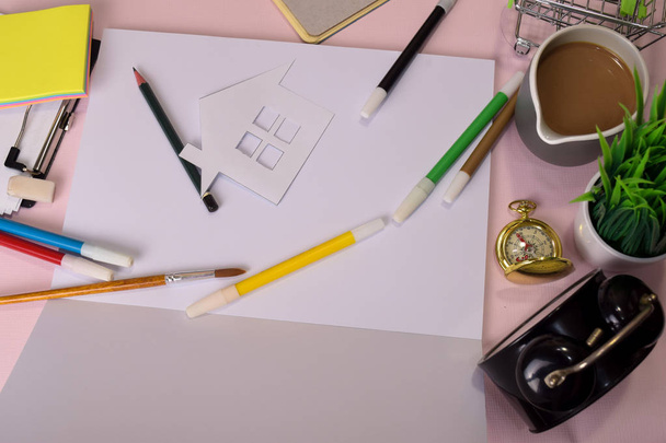 ピンクのテーブルの上に切削紙や図面の家のトップビュー, 開いたノートブックで宿題を行う準備.ワーキングデスクのコンセプトを描く. - 写真・画像